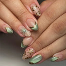 Obroi close-up of hands with decorative nail art featuring flowers and gold accents.