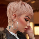 Person with short pink hair, hoop earrings, and tattoos on a blurred background