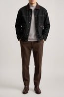 Person wearing a dark denim jacket with a plain background, Obroi
