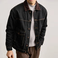Person wearing a dark denim jacket with a plain background, Obroi