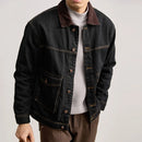 Person wearing a dark denim jacket with a plain background, Obroi