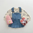Children's outfit with denim overalls, floral shirt, pink beanie, and shoes on a light gray background, Obroi