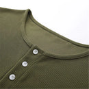 Close-up of a green ribbed knit garment with buttons on a white background, Obroi