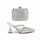 Silver embellished clutch and high-heeled shoes on a white background with 'Obroi' branding.
