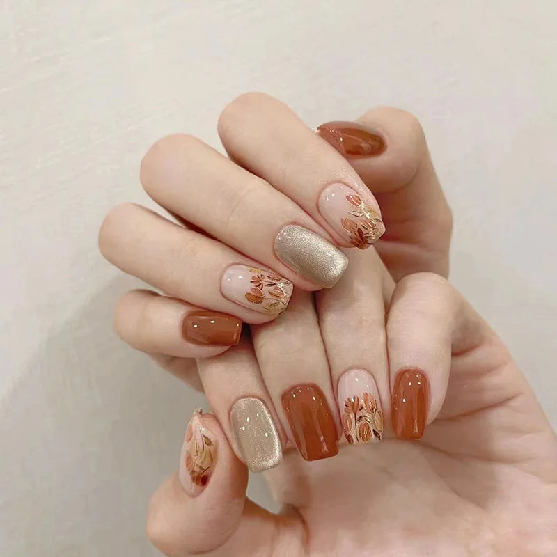 Hand with intricately designed nails featuring gold and brown colors on a neutral background, Obroi