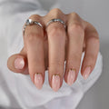 Hand with pink nail polish and silver rings on a neutral background, Obroi