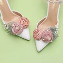 White high-heeled shoes with pink floral decorations on a light green background, Obroi