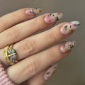 Hand with floral nail art and a decorative ring on a neutral background, Obroi