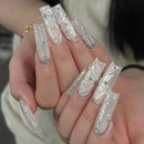 Nails with decorative white and gold designs on a neutral background, Obroi