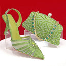 Green high-heeled shoe and matching clutch with gemstones on a red background, Obroi