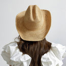 Person wearing a straw hat and white blouse against a plain background, Obroi