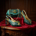 Teal high-heeled shoes and matching handbag with gemstone details on a red fabric background, Obroi