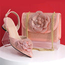 Pink high-heeled shoe and matching handbag with floral design on a red background, Obroi
