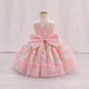 A pink toddler party dress displayed on a dress form mannequin. The sleeveless dress features a large pink bow at the back waist, a V-neckline, and a layered tulle skirt decorated with pastel-colored floral embroidery and sequins, Obroi