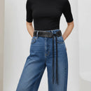 Person wearing blue jeans with a studded belt on a plain background, Obroi
