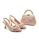 Pair of pink high-heeled shoes with floral details and a matching handbag on a white background, Obroi
