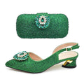 Green glittery shoes and matching clutch with decorative brooches on a white background, Obroi