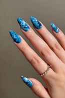 Hand with blue marbled nail polish on a neutral background, Obroi
