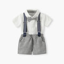 A baby boy's formal outfit consisting of a white short-sleeve button-up shirt, gray textured suspenders with navy blue straps, a gray bow tie, and matching gray shorts, displayed on a clean white background, Obroi