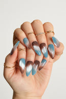 Hand with gradient blue and brown nail art on a blurred background, Obroi