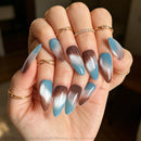 Hand with gradient blue and brown nail art on a blurred background, Obroi