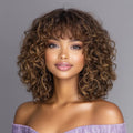 Woman with curly hair wearing an off-shoulder purple top against a gray background, Obroi