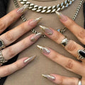 Close-up of hands with gold and silver nail designs and jewelry, Obroi