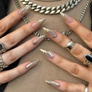 Close-up of hands with gold and silver nail designs and jewelry, Obroi