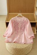 Pink floral blouse on a hanger against a wooden shelf background, Obroi