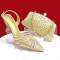 Gold high-heeled shoe and matching handbag with rhinestone details on a red background, Obroi