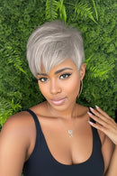 Woman with short gray hair against a green leafy background, Obroi