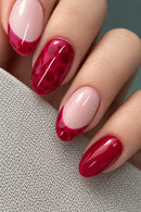 Close-up of manicured fingernails with a glossy French tip design, alternating between deep magenta-pink and pale blush pink, resting on a textured neutral fabric.