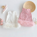 Two children's dresses, one white and one pink with frills, on a light background, Obroi