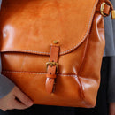 Brown leather backpack with a buckle held by a person, Obroi
