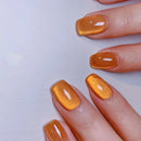 Close-up of a hand with orange nail polish on a light gray background, Obroi