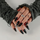 Close-up of hands with black nail polish and multiple rings on a neutral background, Obroi