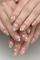 Close-up of hands with pink and gold floral nail art on a neutral background, Obroi