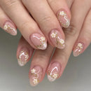 Close-up of hands with pink and gold floral nail art on a neutral background, Obroi