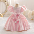 Pink children's dress on a mannequin with decorative elements in a soft, blurred background, Obroi