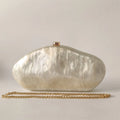 White shell-shaped clutch bag with a gold chain on a light gray background, Obroi