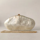 White shell-shaped clutch bag with a gold chain on a light gray background, Obroi