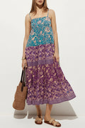 Woman wearing a blue and pink floral dress holding a brown bag on a white background, Obroi