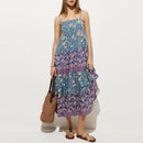 Woman wearing a blue and pink floral dress holding a brown bag on a white background, Obroi