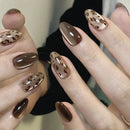 Nails with brown and gold leopard print design on a neutral background, Obroi