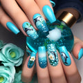 Nails with dolphin and floral design held by a hand with turquoise nail polish, surrounded by turquoise flowers, Obroi