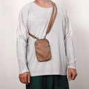 Person wearing a white ribbed sweater with a brown leather crossbody bag on a plain background, Obroi