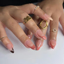 Close-up of a hand with multiple gold rings on a white background, Obroi