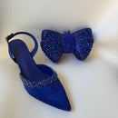 Blue stiletto shoe with embellishments and matching blue bow clutch on a white background, Obroi