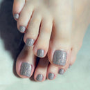 Close-up of feet with silver glitter nail polish on a neutral background, Obroi