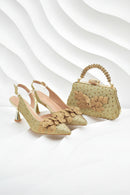 Gold high-heeled shoes and matching handbag on a white background, Obroi